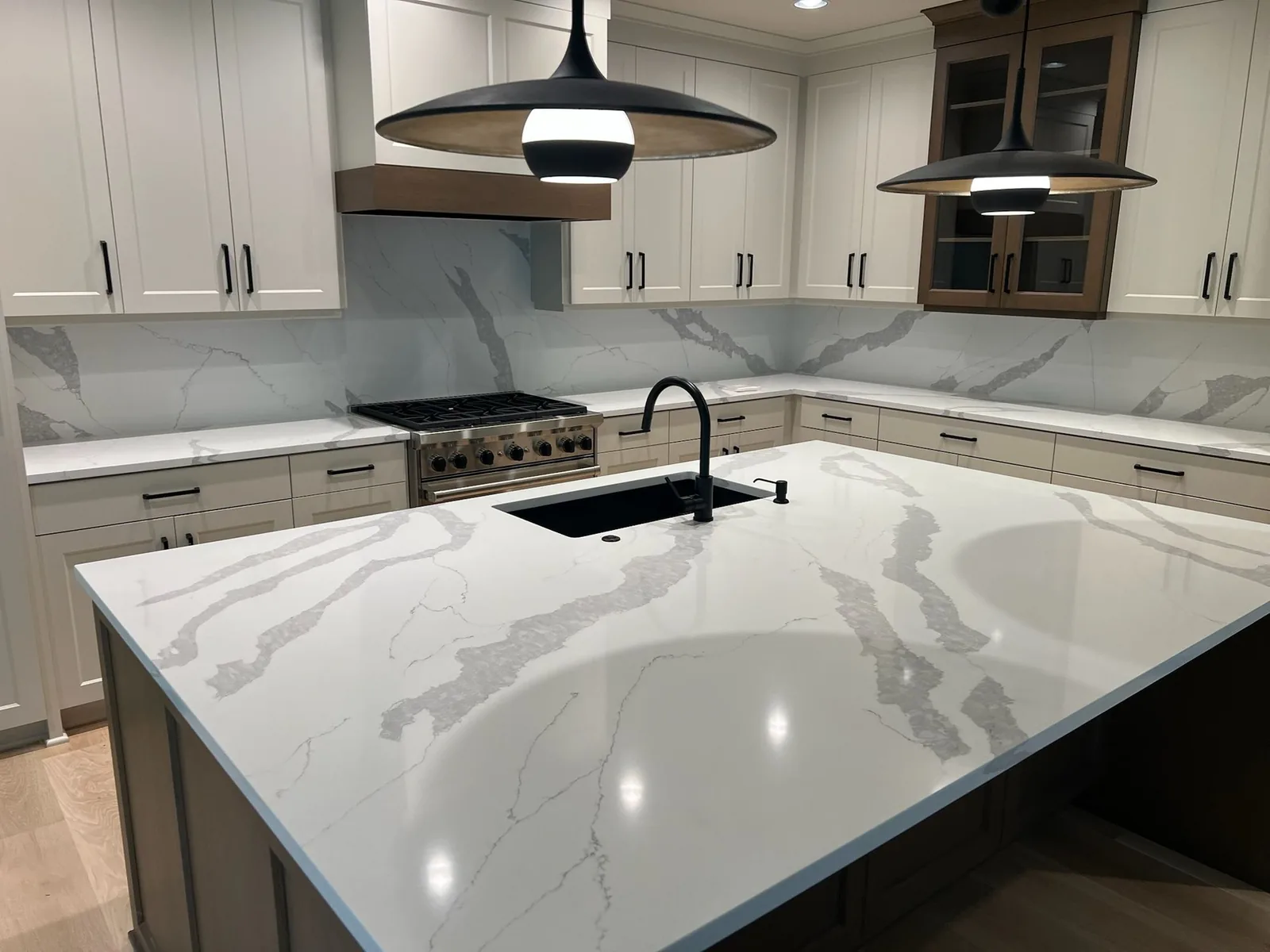 White veined kitchen island countertop with black pendant lights