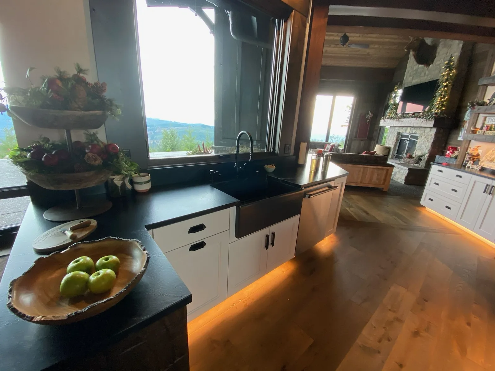 Black countertops with a farmhouse sink and mountain view