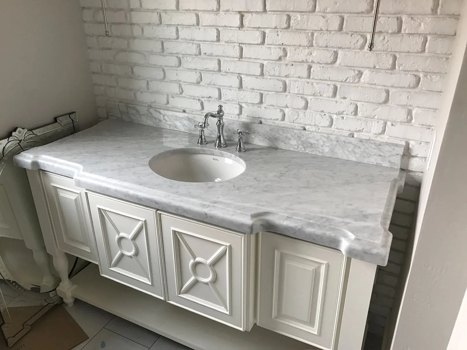 White veined vanity top on a white furniture-style cabinet