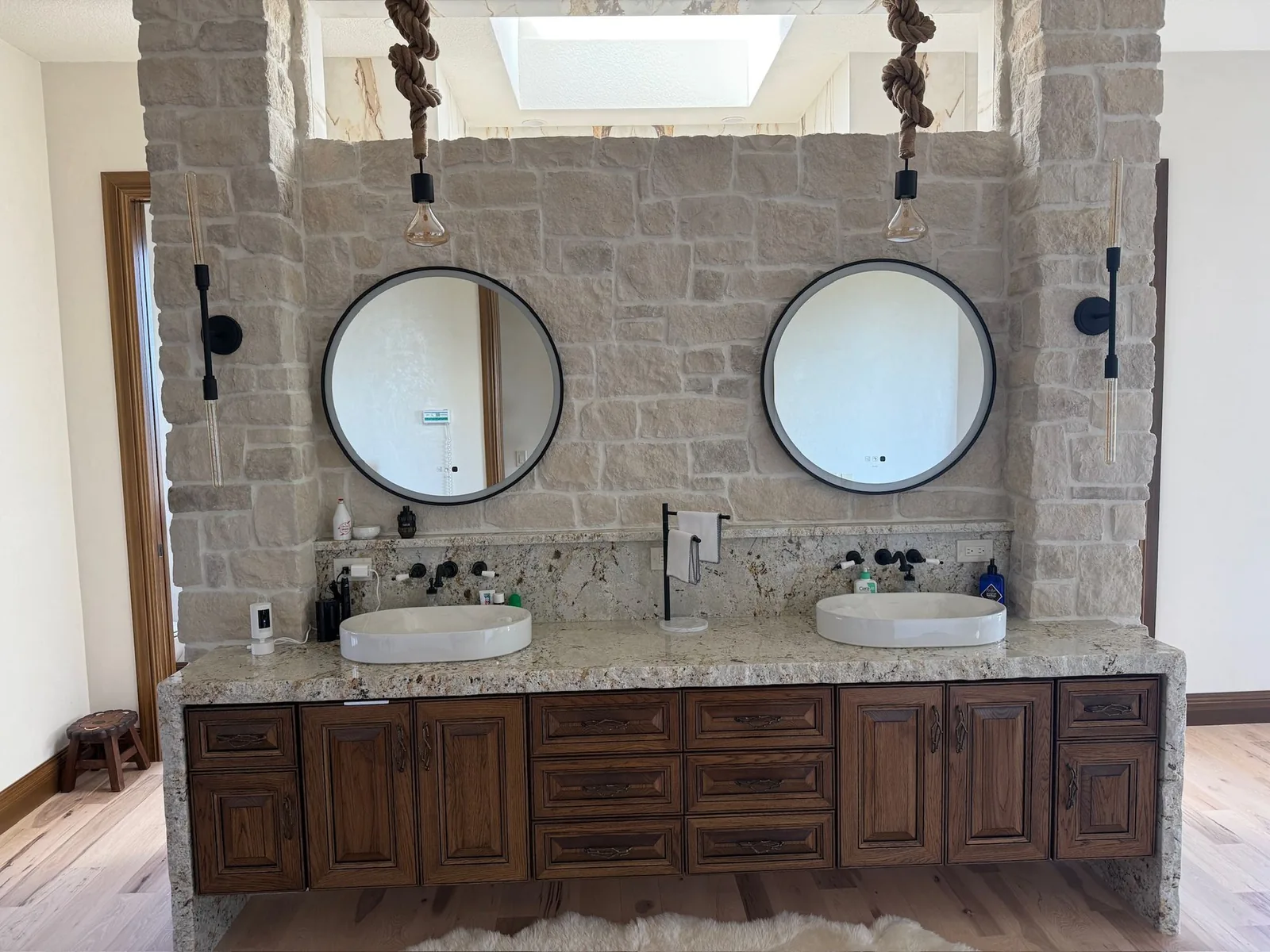 Double vanity with vessel sinks in front of a stone wall