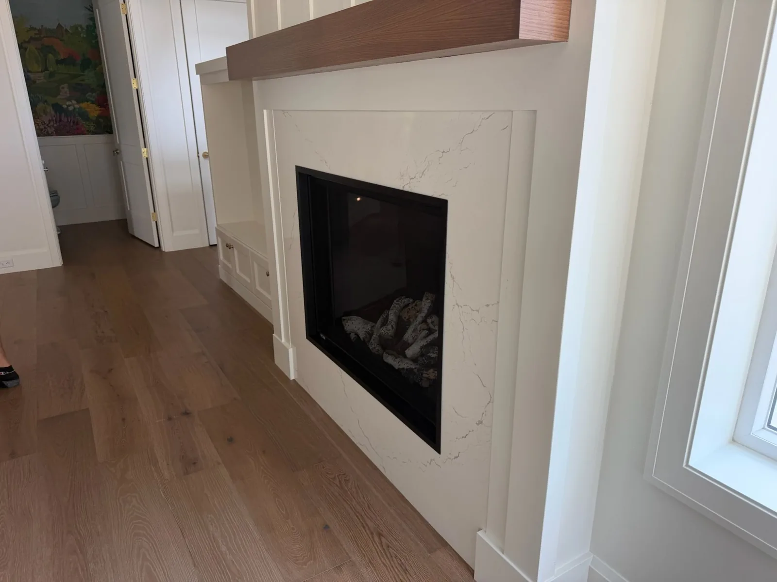 White fireplace surround with a wood mantel